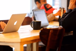 Group working in a cozy cafe with laptops and coffee mugs on a shared table.