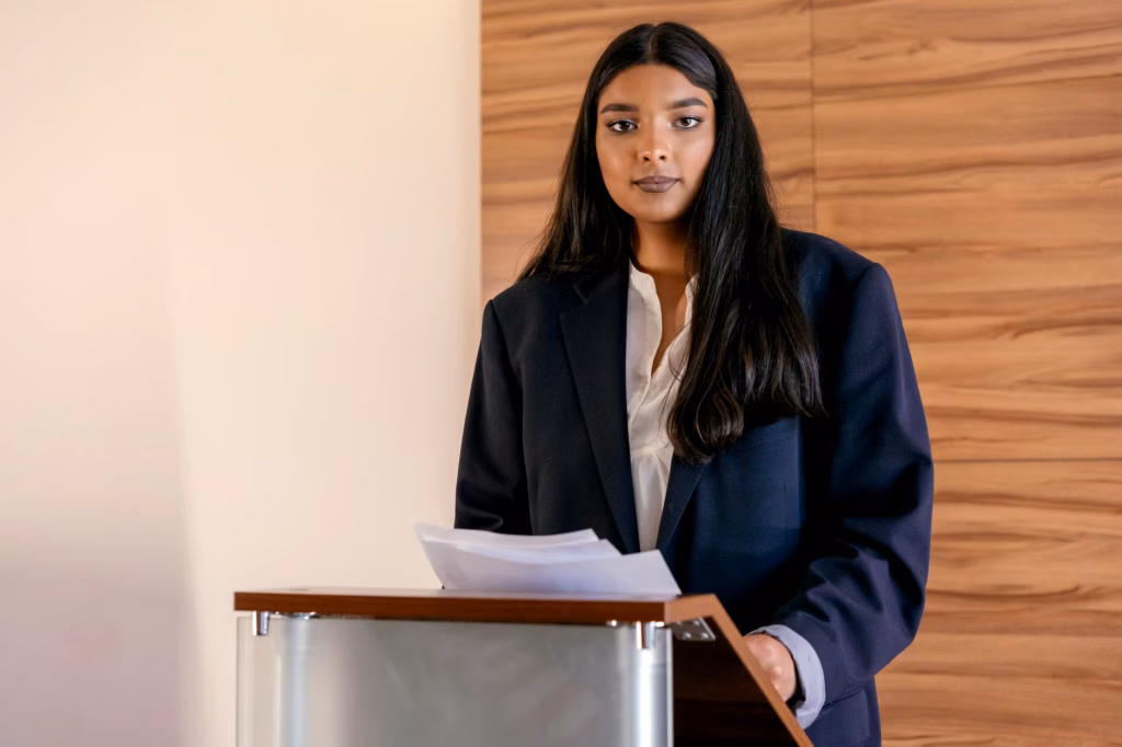 A professional woman leader addresses an audience at a formal higher education event
