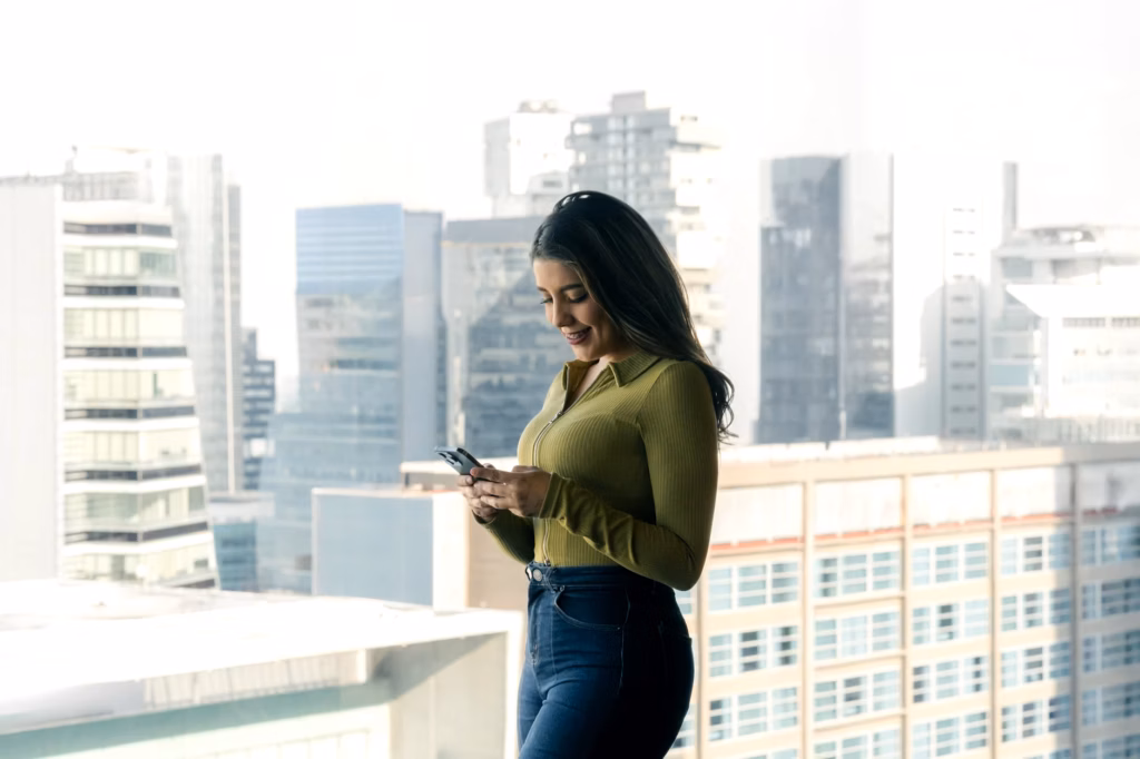 A businesswoman stands at a glass office window overlooking a city, representing corporate ambition