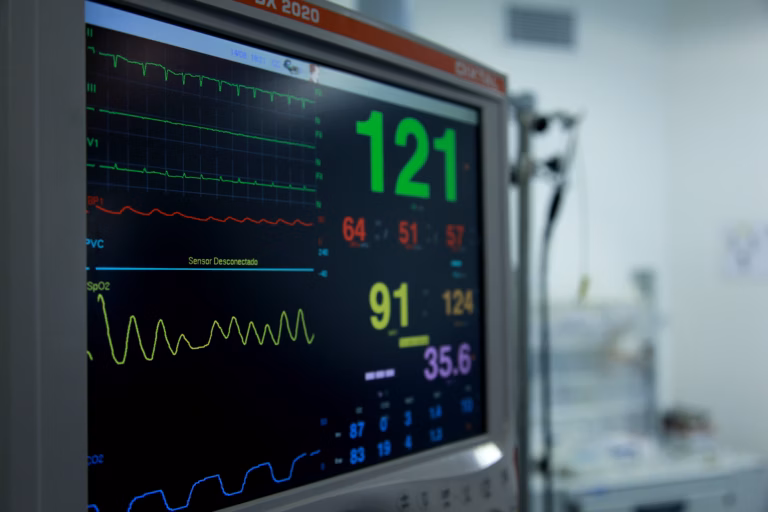 A nurse monitors a patient at an intensive care unit bedside with medical equipment