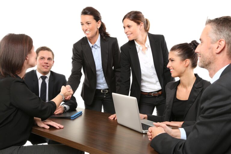 A diverse group of professional women are gathered around a table, actively collaborating and discussing ideas
