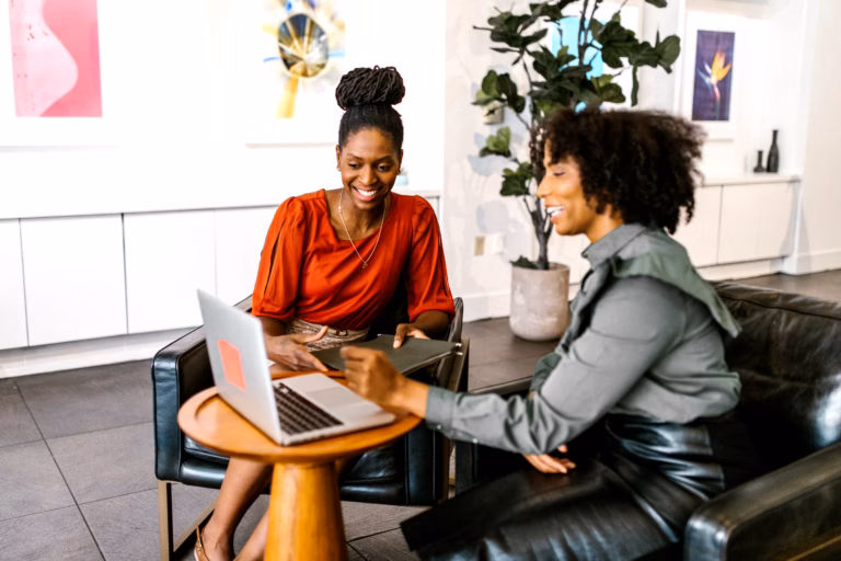 African Governments Urged to Fund Gender Policies for Women Entrepreneurs 2 Two African women in business attire having a serious discussion at a table in a bright office