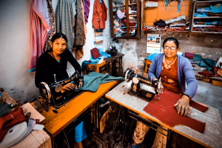 A group of rural women entrepreneurs smiling and working together in an outdoor setting