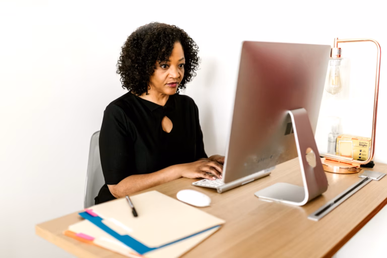 A Black professional woman works at a computer in a bright modern office