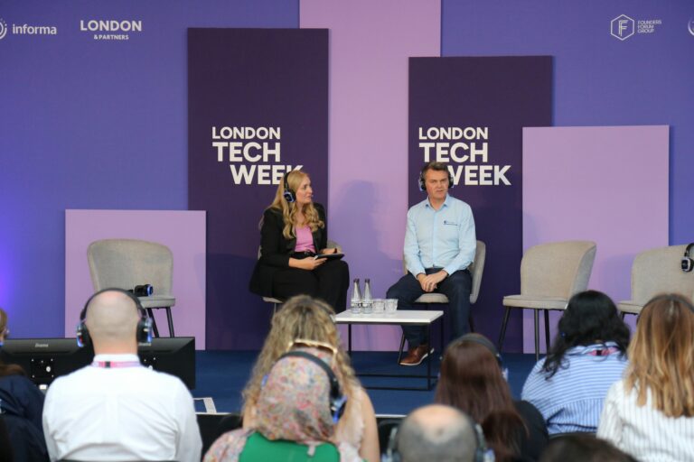 Voting Opens for 2026 Most Influential Women in UK Tech List 2 A woman speaking confidently on stage at a tech conference, addressing an audience