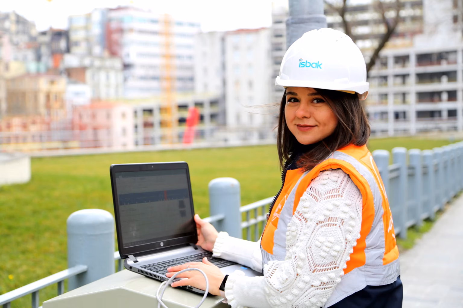 A confident woman engineer in a hard hat smiles, standing in an industrial or research setting