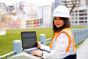 A confident woman engineer in a hard hat smiles, standing in an industrial or research setting