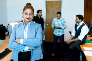 A confident professional woman stands in a bright, modern office with a subtle healthcare background
