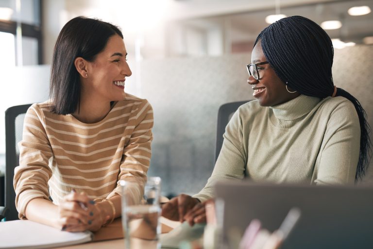 How Managers Can Support Women Through Motherhood and Career Transitions 2 Two diverse colleagues share ideas in a modern office setting during a collaborative meeting