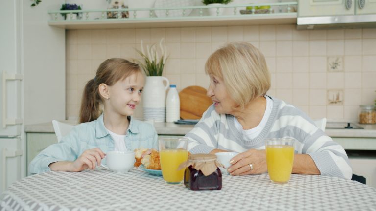 Why Experienced Women Are Leaving Ireland's Workforce Early 1 A grandmother and granddaughter sharing a joyful breakfast at home, bonding over orange juice and pastries