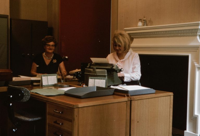 two women sitting beside desk