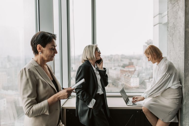 Three mature businesswomen engaged in work at a modern office, promoting teamwork and productivity