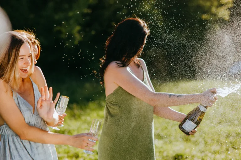 Joyful women celebrating with champagne in a sunny outdoor setting