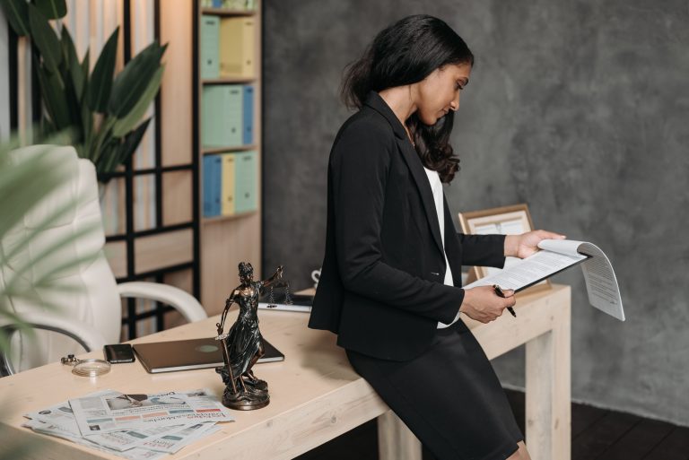 Document Bad Experiences: Irish Group Seeks 300 Women's Accounts 1 A woman reviews documents beside a justice statuette, an illustrative legal scene