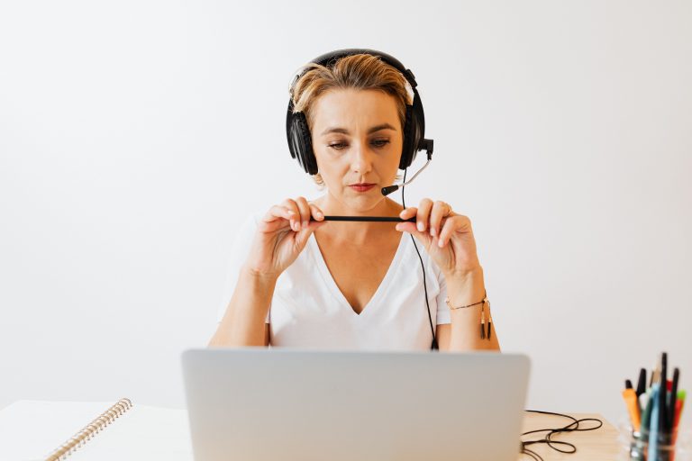 A woman wearing a headset behind a laptop, an illustrative remote work scene