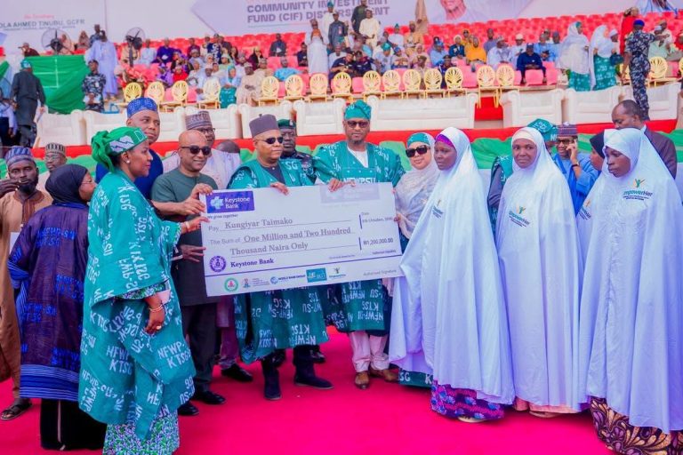 Katsina women and officials holding a ceremonial cheque at the programme launch