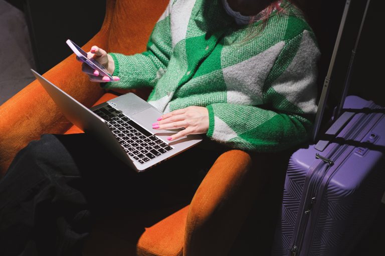 Nigeria’s Digital Economy Leaves Women Facing Access Barriers 2 Woman using a smartphone beside a laptop on an armchair