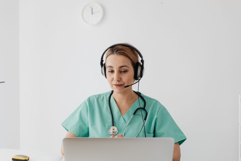 Healthcare professional wearing a headset at a laptop