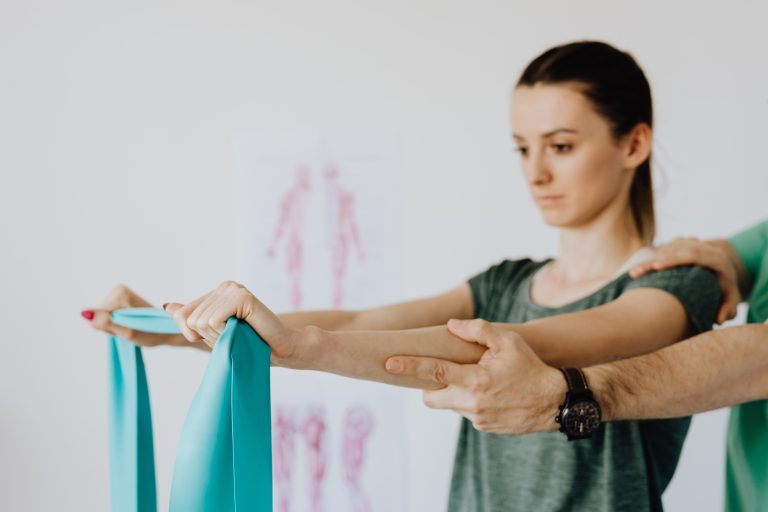 Therapist assisting a woman with an exercise band