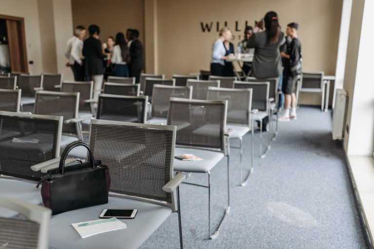 An empty conference room with chairs and a group of people gathered at the back